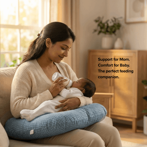Woman holding a baby while using a nursing pillow in a cozy living room.