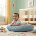 Baby lying on a Baby Feeding Pillow in a nursery with a crib and toys in the background.
