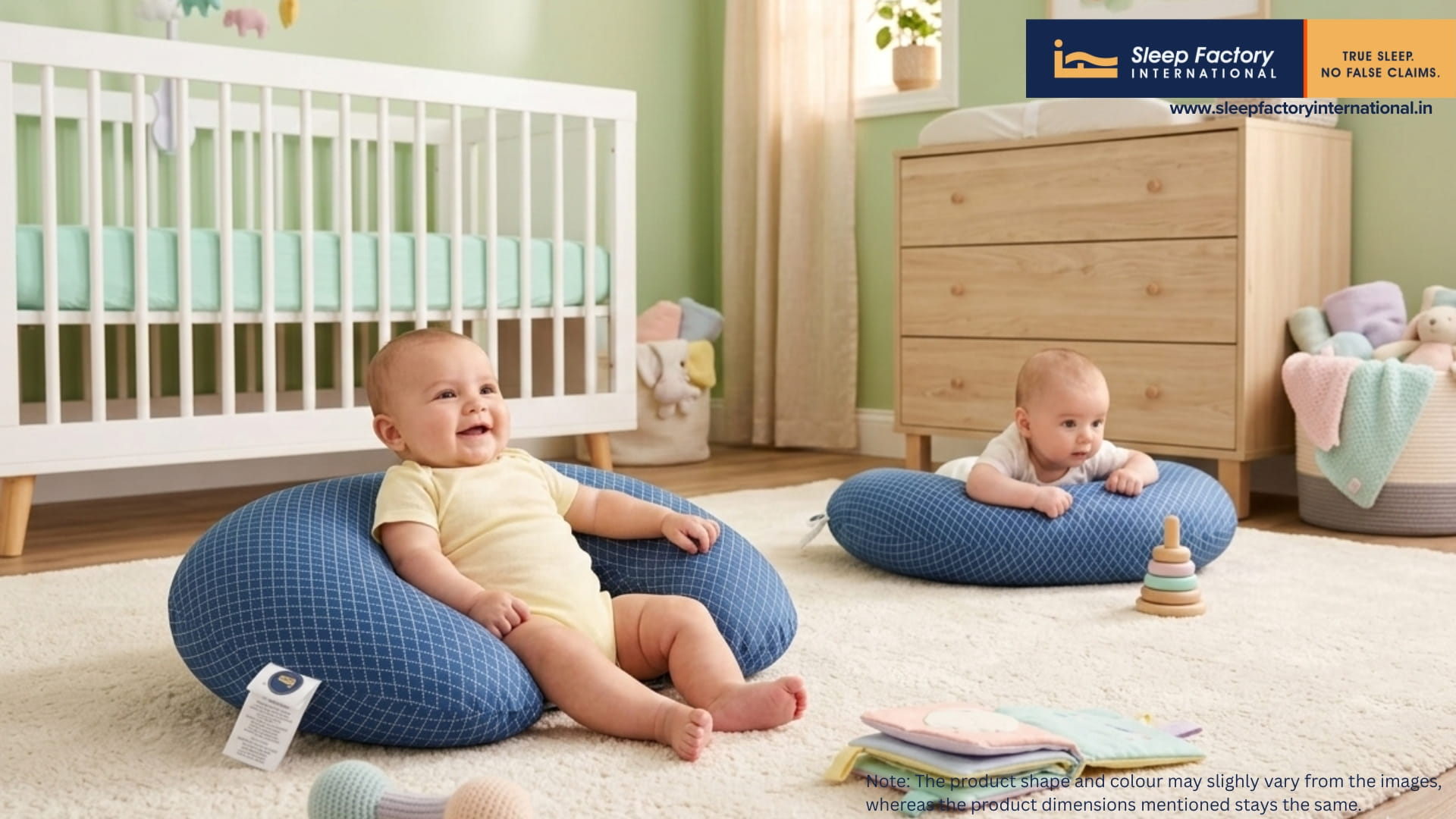 Two babies sitting on blue baby pillows in a nursery room with furniture and decor.