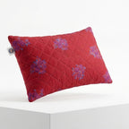 Red quilted pillow with floral patterns on a white background