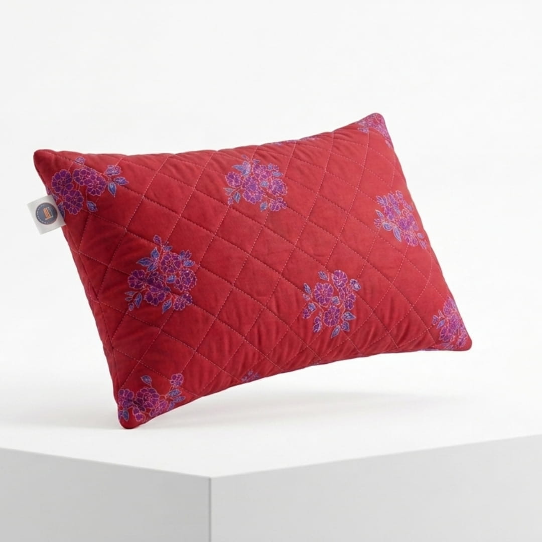 Red quilted pillow with floral patterns on a white background