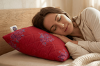 Woman lying on a bed with a red pillow and beige blanket